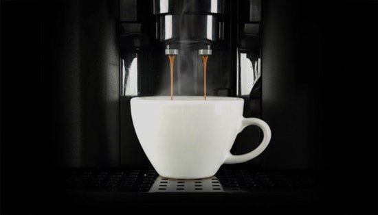 Koffiemachine zet espresso in een witte kop.