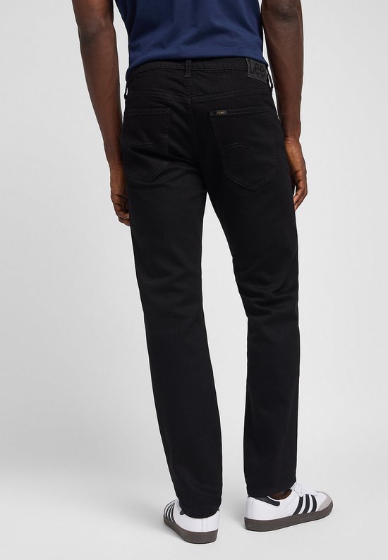 Achterkant van een man in zwarte jeans en met Adidas sneakers.