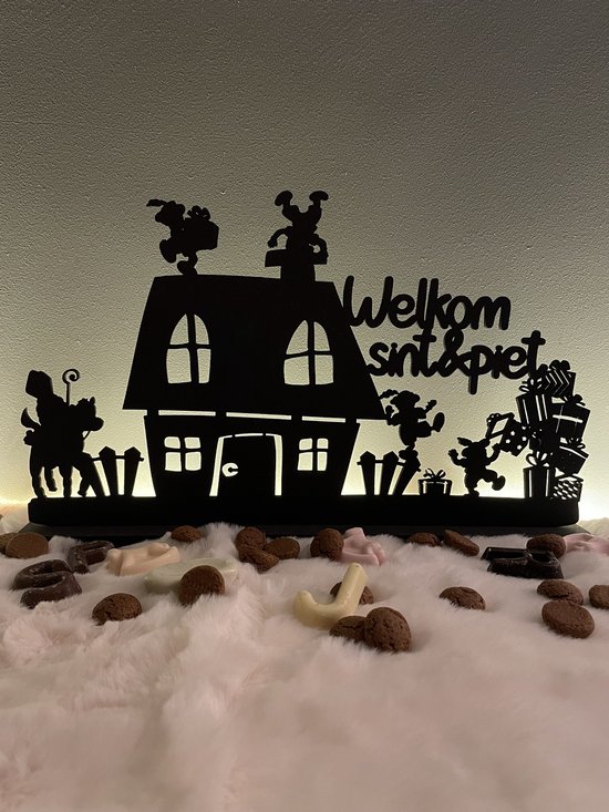 Zwart silhouet van een huis met 'Welkom sint & piet', kinderen, een paard en cadeautjes.