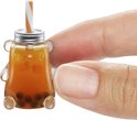 Vinger die een miniatuur beer-vormige boba theebeker vasthoudt met oranje gestreepte rietje.