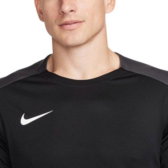Close-up van een zwart dri-fit sportshirt van Nike met donkergrijze schouderdetails en witte swoosh.