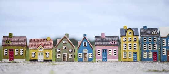 Rij van kleurrijke keramieken huisjes met verschillende daken en deuren, waaronder gele, roze en blauwe huizen.