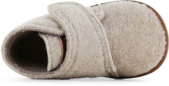 Close-up van een beige vilten slofje, van bovenaf gezien, met klittenbandsluiting.