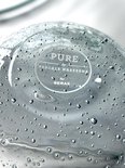 Onderkant van een glazen karaf met 'PURE by PASCALE NAESSENS for SERAX' tekst.