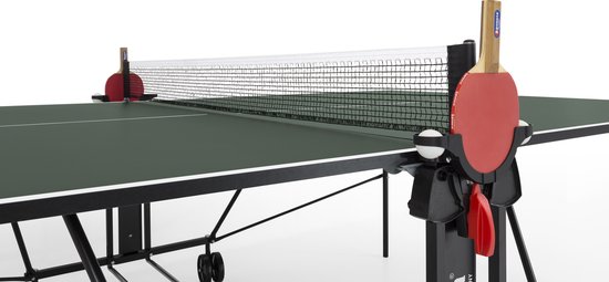 Een groene tafeltennistafel met een net in het midden. Twee rode batjes met houten handvatten staan in houders aan weerszijden van het net.