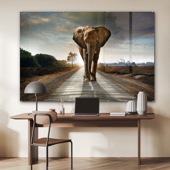 Un éléphant marche sur une route au coucher du soleil, affiché sur un bureau.