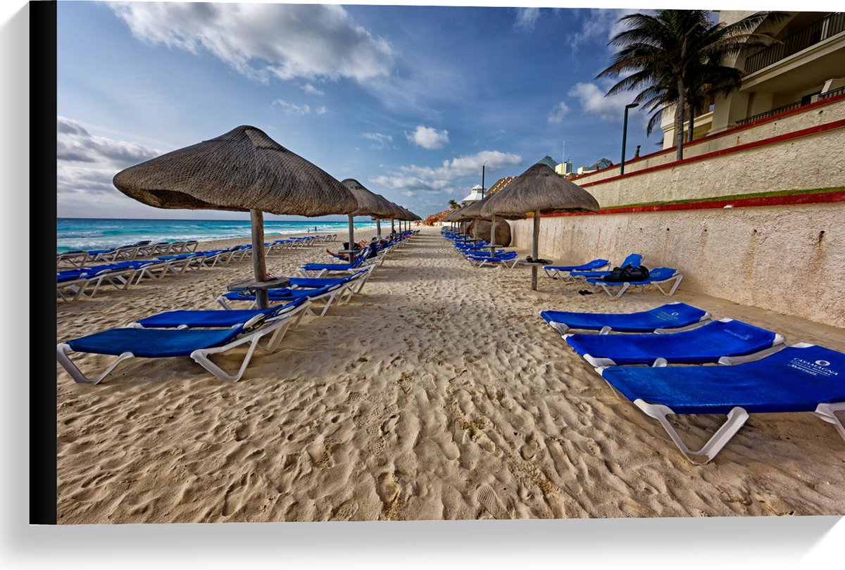 Canvas - Blauwe Ligbedden op Strand met Rieten Parasols - 60x40 cm Foto op Canvas Schilder