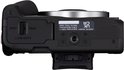 Bovenaanzicht van de zwarte Canon EOS R50 systeemcamera met open batterijvak.