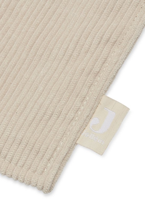 Detail van beige corduroy stof met een Jollein label.