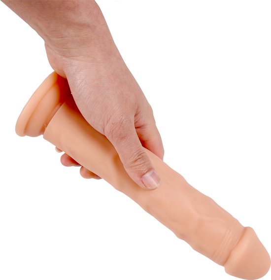 Een hand houdt een beige dildo met gerimpelde schacht en platte basis vast.