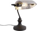 Lampe de banquier noire avec abat-jour en verre gris et ampoule visible.