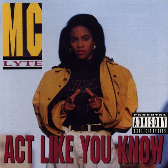 MC Lyte met "Act Like You Know" albumtitel. Ze draagt een gele jas, zwarte Nike top en witte broek.