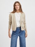 Model draagt een beige gebreid vest met witte top en jeans.