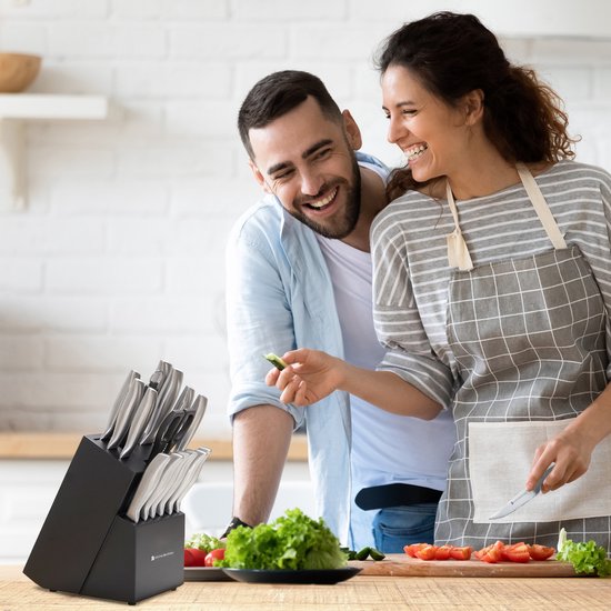 Een stel lacht in een keuken met een KitchenBrothers messenset in een blok.