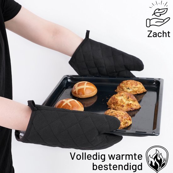 Mains portant des gants de cuisine noirs sortant une plaque de cuisson avec des petits pains et des scones du four.
