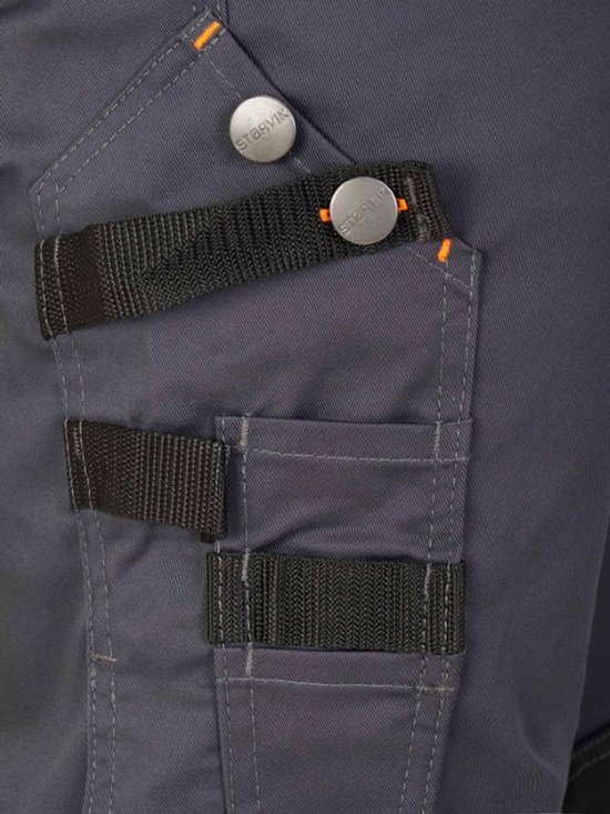 Détail du pantalon de travail gris foncé avec coutures orange, boutons et boucles noires.