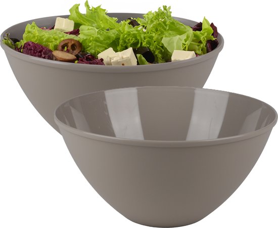 Grijze saladekom gevuld met sla, tomaat, kaas en olijven, met een lege kom ervoor.