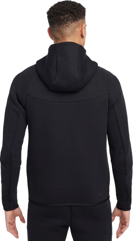Achterkant van een zwarte Nike Tech Fleece hoodie met rits, gedragen door een man.