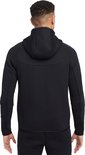 Achterkant van een zwarte Nike Tech Fleece hoodie met rits, gedragen door een man.