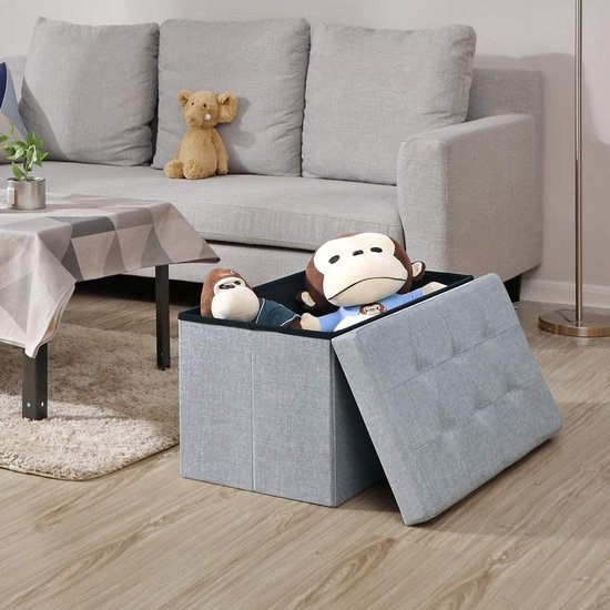 Grijze opbergkist in een woonkamer, gevuld met twee apenknuffels, deksel staat open.
