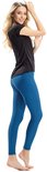 Vrouw in zwarte top en blauwe legging, staand op witte achtergrond.