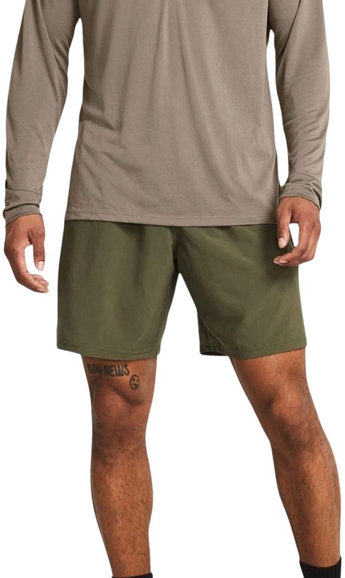 Man in legergroene sportshort, beige longsleeve shirt en zwarte sokken.