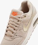 Close-up van beige Nike Air Max Command PRM sneaker met oranje Nike Air logo op de tong, beige veters, gouden swoosh en Air unit.