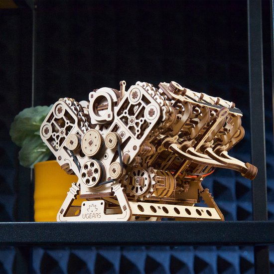 Houten V8-motor model met complexe mechanica, tentoongesteld op een zwarte plank.