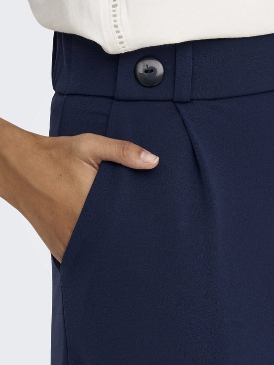 Detail van een marineblauwe wijde broek met een open zak en een knoop.