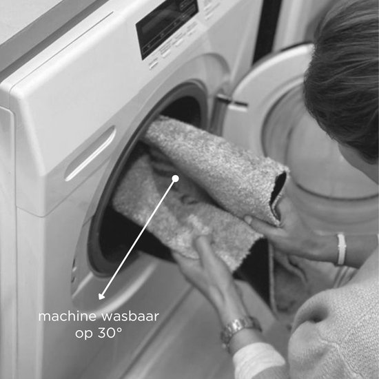 Een vrouw doet een lichtgrijze deurmat in een wasmachine, met de tekst 'machine wasbaar op 30°'.