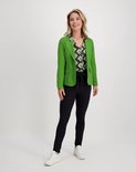 Model met zwarte slim fit broek, groen jasje en blouse met grafische print.