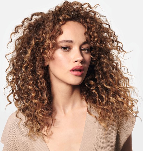 Model met lang, golvend bruin haar en een beige topje.