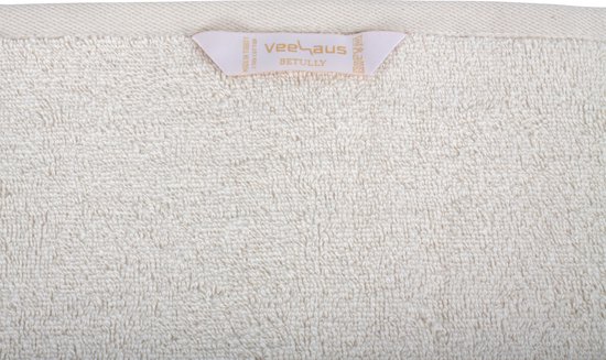 Dichtbij opname van een crèmekleurige handdoek met een label van Veehaus en Betully.