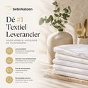 Stapel witte lakens met een vaasje eucalyptus ernaast. Tekst: Dé #1 Textiel Leverancier.