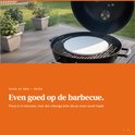 Witte pizzasteen op een grill met gloeiende kolen, op een houten terras.