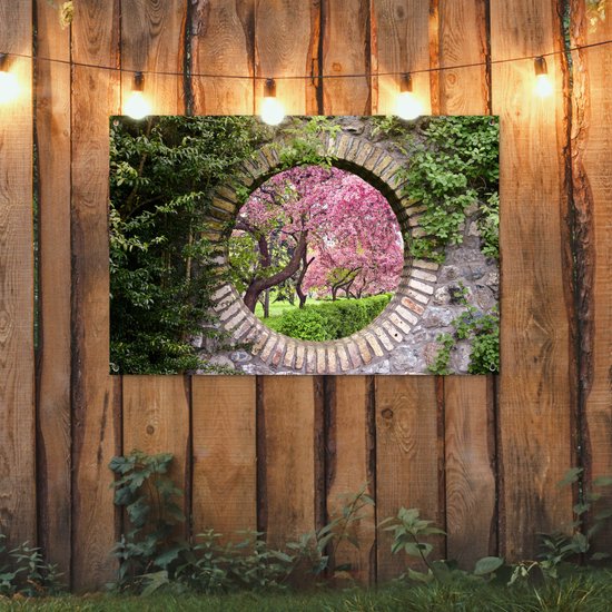 Une affiche de jardin avec des arbres roses en fleurs à travers une ouverture circulaire en pierre, accrochée à une clôture en bois avec des lumières.