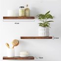 Drie zwevende donkerbruine houten planken aan een witte muur met decoraties.