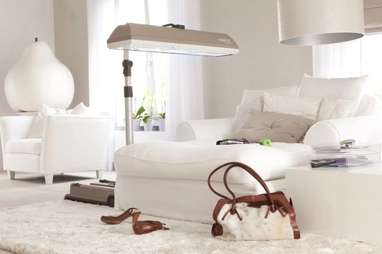 Beige zonnehemel in een woonkamer, naast een witte sofa en fauteuil.