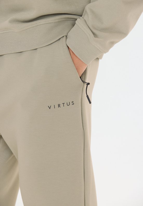 Close-up van de zak van een beige trainingsbroek met zwart trekkoord en logo.