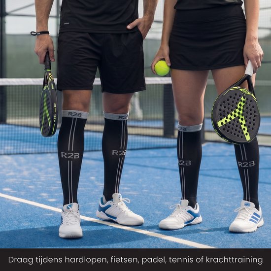 Man en vrouw met zwarte R2B compressiekousen op een blauw padelveld, beiden met een padelracket.