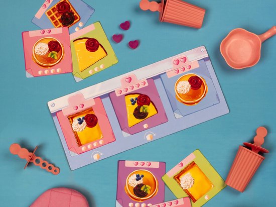 Een verzameling speelkaarten en speelstukken met zoete gebakjes op een blauwe achtergrond.