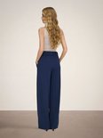 Model draagt donkerblauwe wijde broek met beige top.