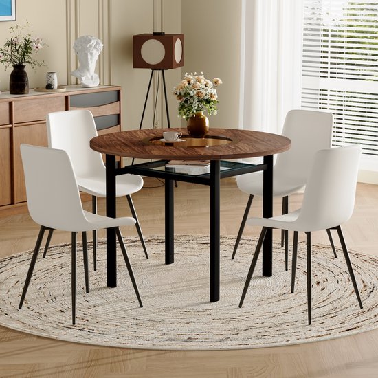 Table à manger ronde avec plateau aspect bois et quatre chaises blanches sur pieds noirs, dans une salle à manger lumineuse.