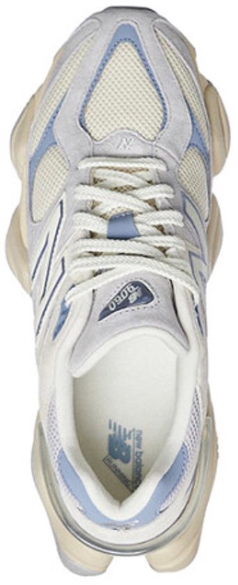 Bovenkant van een lichtgrijze New Balance 9060 sneaker met beige en lichtblauwe details, veters en een witte binnenzool.