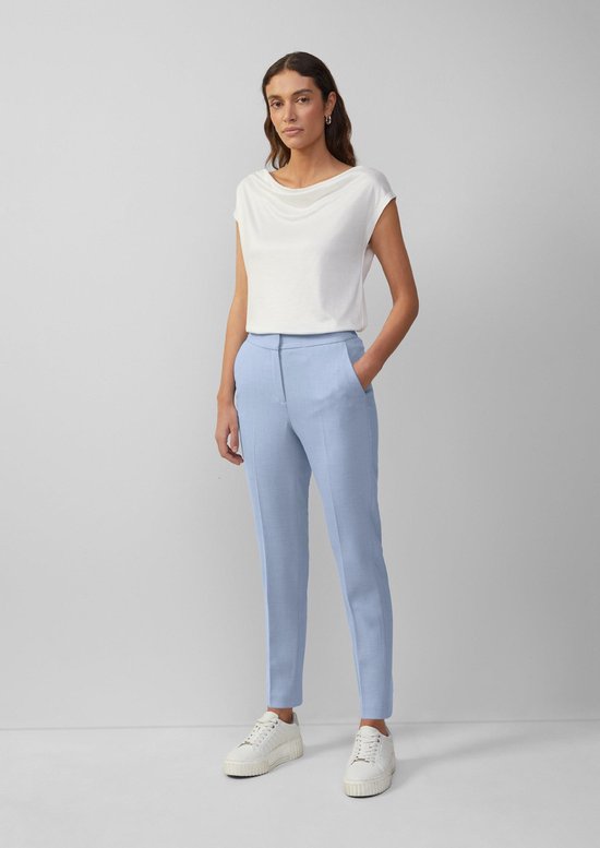 Model draagt een lichtblauwe broek met rechte pijpen en een witte top.