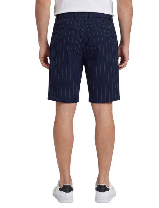 Man draagt donkerblauwe korte broek met krijtstrepen, van achteren gezien.
