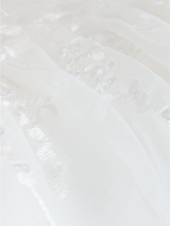 Close-up van de witte tule stof met subtiel bloemenborduursel.