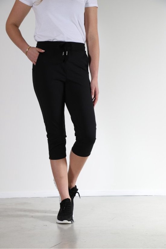 Zwarte capri broek met elastische tailleband, trekkoord, zak en sneakers.