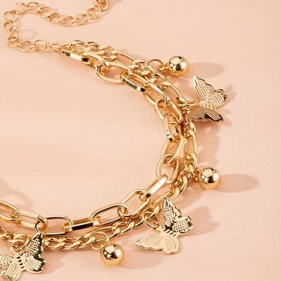 Gouden schakelarmband met vlinder- en bolvormige bedels.