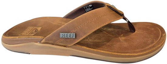 Bruine Reef teenslipper met leren bandjes, bruine zool en zichtbaar Reef logo.